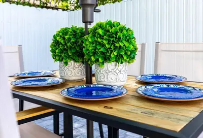 a wooden table with blue plates and green plants at Serenity Lodge II Condo in Miami