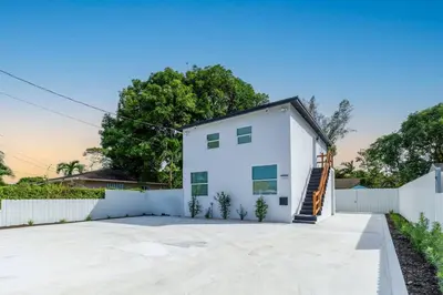 a white house with a white fence at Serenity Lodge II Condo in Miami