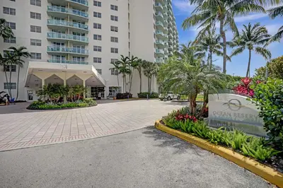 a walkway in front of a building with palm trees at Ocean Reserve Condominium in Miami Beach