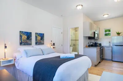 a white bedroom with a large bed and a kitchen at Azure - Mins to Las Olas & Beach in Fort Lauderdale