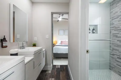 a bathroom with two sinks and a shower with a bed at Lauderdale Bliss - Mins to Las Olas & Beach in Fort Lauderdale