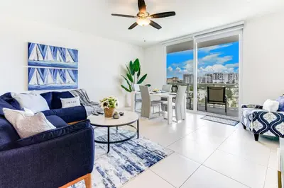 a living room with a blue couch and a table at Tiffany Emerald - Rooftop Pool, Gym, & Walk to Beach in Fort Lauderdale