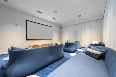 a living room with blue couches and a projection screen at Tiffany Emerald - Rooftop Pool, Gym, & Walk to Beach in Fort Lauderdale