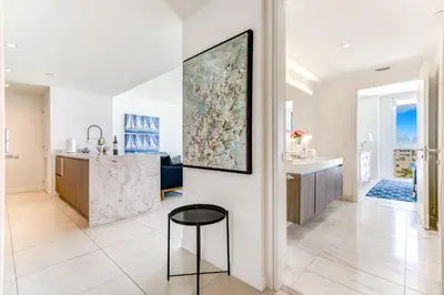 a kitchen and living room in a house with a painting on the wall at Tiffany Emerald - Rooftop Pool, Gym, & Walk to Beach in Fort Lauderdale