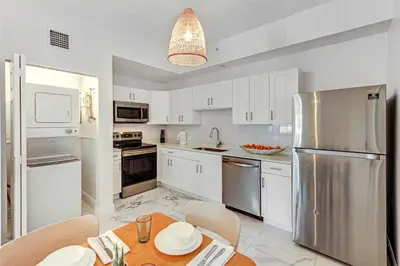 a kitchen with white cabinets and a stainless steel refrigerator at Wynwood Jumbo - Sleeps 16 & free parking in Miami