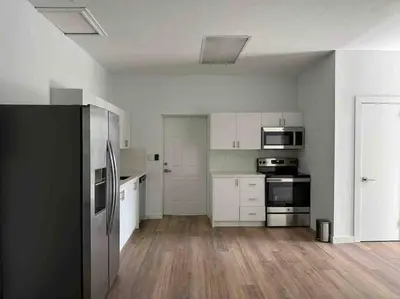 a kitchen with white cabinets and a black refrigerator at Stylish StudioBrickellLittle Havana-ItalianPlaza in Miami