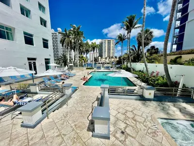 a resort with a swimming pool and people sitting in chairs at Condo, Breathtaking Water views, King Suite, Hilton Property in Fort Lauderdale