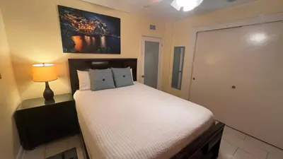 a bedroom with a white bed with a lamp and a door at Billy's Resort- Men Only - Solo Hombres in Wilton Manors