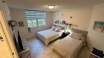 a bedroom with two beds and a tv and a window at Deluxe Yacht Club Condo Near the Beach in Miami
