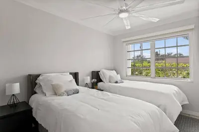 a white bedroom with two beds and a window at 3br Oasis near Coral Gable in Miami