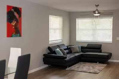 a living room with a black couch and a table at Cozy and Modern Vacation Home in Hallandale Beach