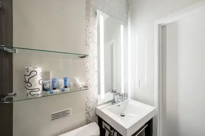 a white bathroom with a sink and a mirror at Ithaca in Miami Beach