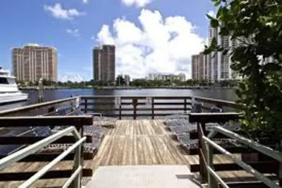 a dock with a boat in the water with buildings at Pet-Friendly Aventura Pool, Beach, Golf, Gym in Aventura