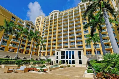 a large yellow building with palm trees in front of it at Leave the Worries Behind & Relax in Our Suite! in Miami