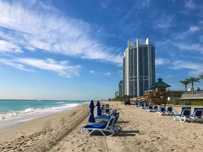 a beach with lounge chairs and a tall building at Condominium Sunny Isles Ocean Reserve in Sunny Isles Beach