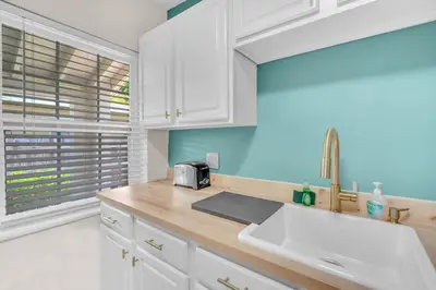 a kitchen with white cabinets and a sink and a window at Bluewave Bungalow - #1 Charming & Comfortable 2 1 in Dania Beach