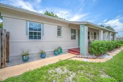 a white house with plants in front of it at Bluewave Bungalow - #1 Charming & Comfortable 2 1 in Dania Beach