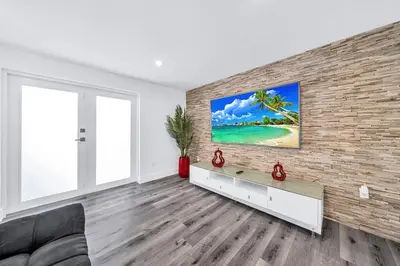 a living room with a tv on a brick wall at 3 2 Family friendly Brand New Home w Pool in Miami