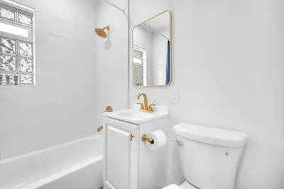 a white bathroom with a sink and a mirror at Bluewave Bungalow - #2 Charming & Relaxing 2 1 in Dania Beach