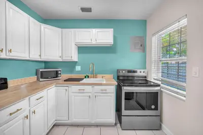 a kitchen with white cabinets and a blue wall at Bluewave Bungalow - #2 Charming & Relaxing 2 1 in Dania Beach