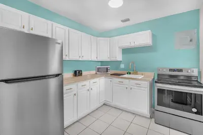 a kitchen with white cabinets and a stainless steel refrigerator at Bluewave Bungalow - #2 Charming & Relaxing 2 1 in Dania Beach