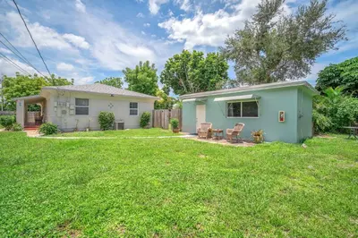 a small blue house in a yard at Blue Wave Bungalow - 1 1 - Stylish in Dania Beach