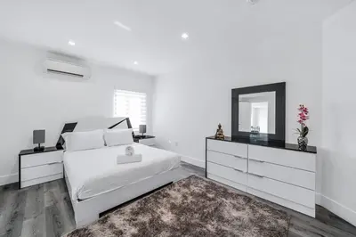 a white bedroom with a bed and a mirror at Homey Studio near the Airport and Water Park in Miami