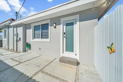 a white building with a door and a fence at Homey Studio near the Airport and Water Park in Miami