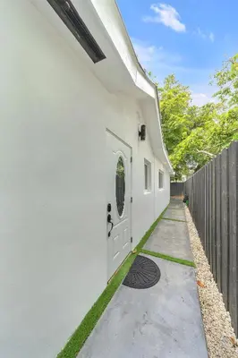 a white building with a door and a fence at Mykonos Home - 2 2 Cozy and Charming Duplex in Miami