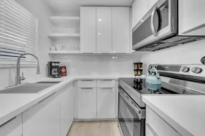 a white kitchen with white cabinets and a sink at Mykonos Home - 2 2 Cozy and Charming Duplex in Miami