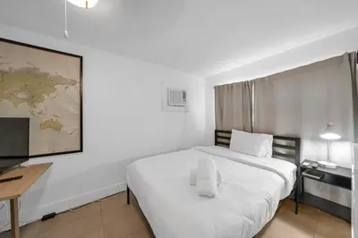 a white bedroom with a large white bed and a desk at Renovated Gem: Prime Spotless Ideal in Miami