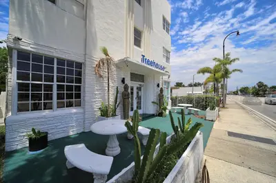 a white building with a table and chairs on the sidewalk at Treehouse Hotel in Miami