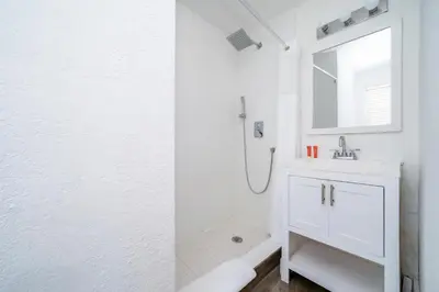 a white bathroom with a sink and a mirror at Treehouse Hotel in Miami