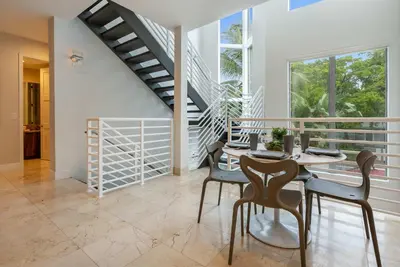 a dining room with a table and chairs and a staircase at 4-Bed + Den with pool in Las Olas Ft Lauderdale in Fort Lauderdale