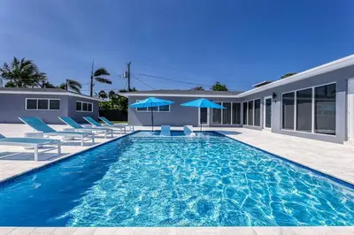a swimming pool with blue chairs and a house at Sunshine Manor 2009 in Fort Lauderdale