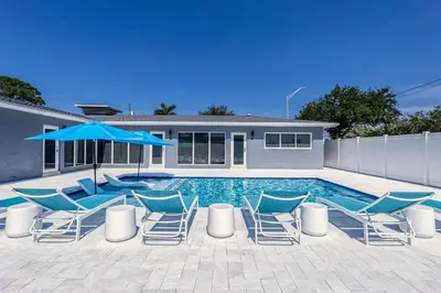 a swimming pool with chairs and a blue umbrella at Sunshine Manor 2009 in Fort Lauderdale