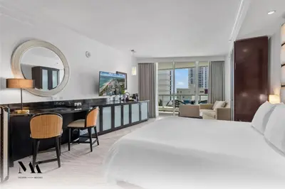 a hotel room with a large bed and a desk at FontaineBleau Resort Balcony w Ocean and City View in Miami Beach