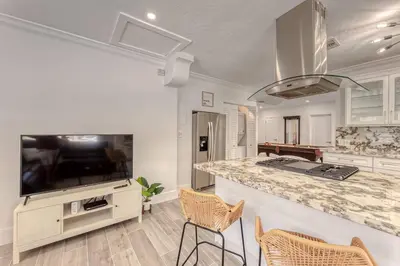 a kitchen with a bar with chairs and a tv at Mango Manor - Walk to Las Olas! in Fort Lauderdale