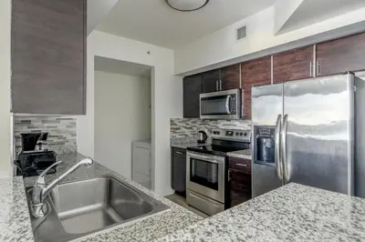 a kitchen with stainless steel appliances and wooden cabinets at Coral Gables 2br w wd pool gym near shops MIA-83 in Miami