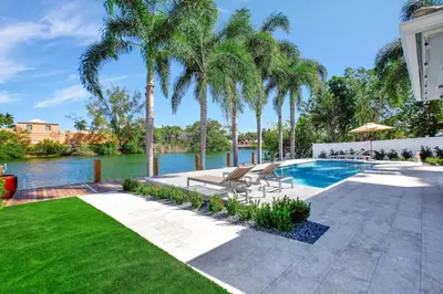 a swimming pool with palm trees in a yard at Lakefront Family Fun Home with Private Dock 3BR 2B in Fort Lauderdale