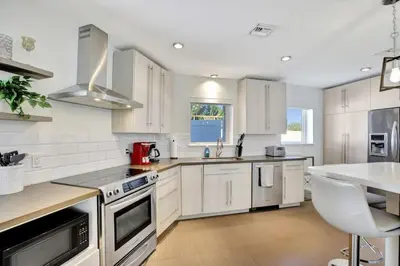 a kitchen with white cabinets and a white table at Lakefront Family Fun Home with Private Dock 3BR 2B in Fort Lauderdale