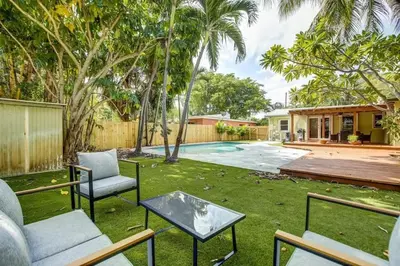 a yard with chairs and a table and a pool at Tranquil Poolside Bliss Pergola Deck Turf Yard in Fort Lauderdale