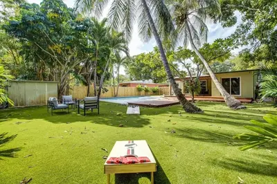 a backyard with a table and chairs and a pool at Tranquil Poolside Bliss Pergola Deck Turf Yard in Fort Lauderdale