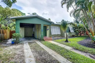 a green house with a garage and palm trees at Tranquil Poolside Bliss Pergola Deck Turf Yard in Fort Lauderdale
