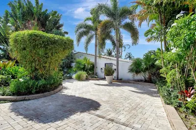 a garden with palm trees and a brick walkway at Wilton on the water courtyard and Heated Pool in Fort Lauderdale