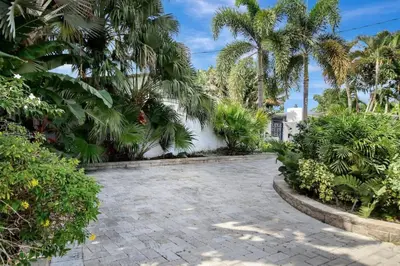 a garden with palm trees and a brick walkway at Wilton on the water courtyard and Heated Pool in Fort Lauderdale