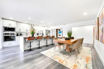 a white kitchen with a wooden table and chairs at The World's Mansion - Game Room, 9 Bedrooms, Htd Pool, Mini Golf, BBQ in Tamiami