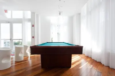 a room with a pool table and two white chairs at Beautiful Loft in Downtown Miami For 4 people 2208 in Miami