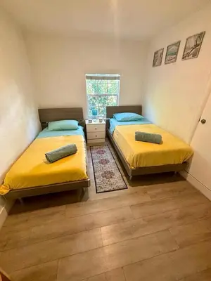 two beds in a small room with yellow sheets at Nice 2 Twin bedroom - Best central location in Miami - Luggage storage, parking and Laundry for free!!!! in Miami