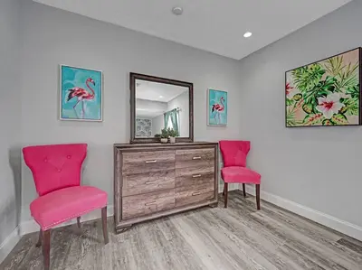 two pink chairs in a room with a dresser and a mirror at Hot Tub! Roof Top! Firepit! Boat Dock! in Fort Lauderdale